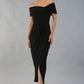 brunette model wearing diva catwalk vegas calf length black midaxi dress with wide bardot neckline and open shoulders with a large opening at the front of the skirt with pleating coming down long skirt front 