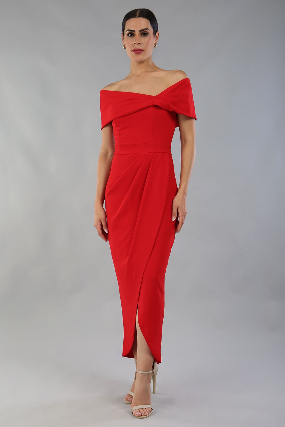 model wearing diva catwalk vegas calf length midaxi dress with wide bardot neckline and open shoulders with a large opening at the front of the skirt with pleating coming down long skirt front in scarlet red