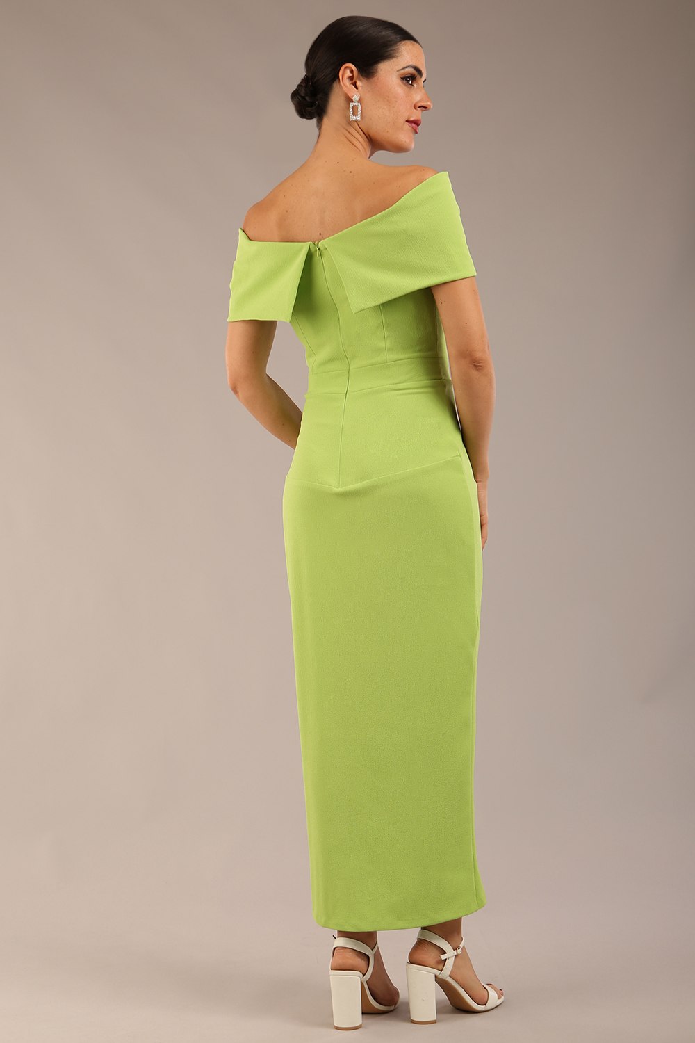 brunette model wearing diva catwalk vegas calf length lime green midaxi dress with wide bardot neckline and open shoulders with a large opening at the front of the skirt with pleating coming down long skirt back