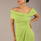 brunette model wearing diva catwalk vegas calf length lime green midaxi dress with wide bardot neckline and open shoulders with a large opening at the front of the skirt with pleating coming down long skirt front 