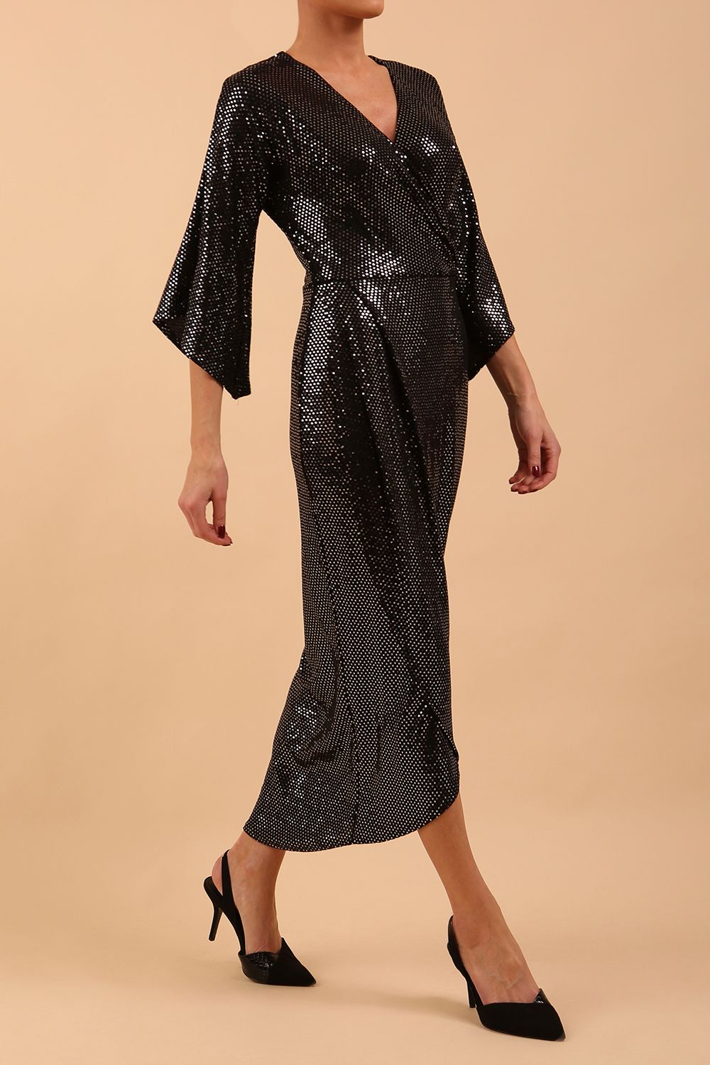 Brunette model wearing diva catwalk Glitterati Midaxi Sparkle Dress in Black in Jersey sparkle and ITY lining with wrap dress style and 3/4 length bell sleeves front side