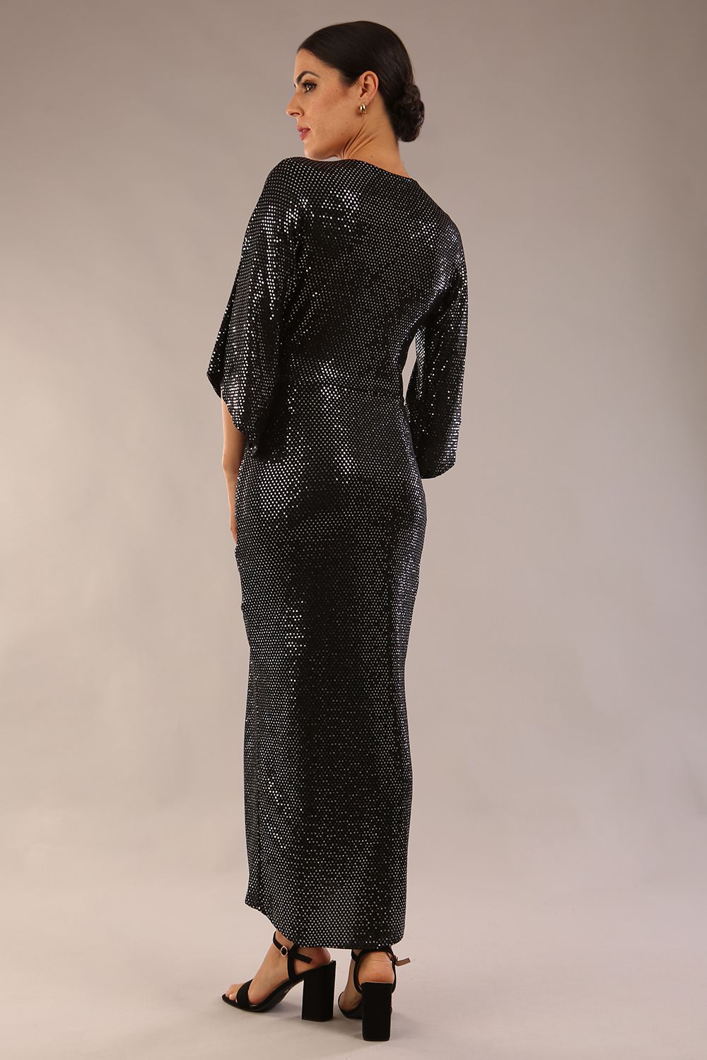 Brunette model wearing diva catwalk Glitterati Midaxi Sparkle Dress in Black in Jersey sparkle and ITY lining with wrap dress style and 3/4 length bell sleeves back