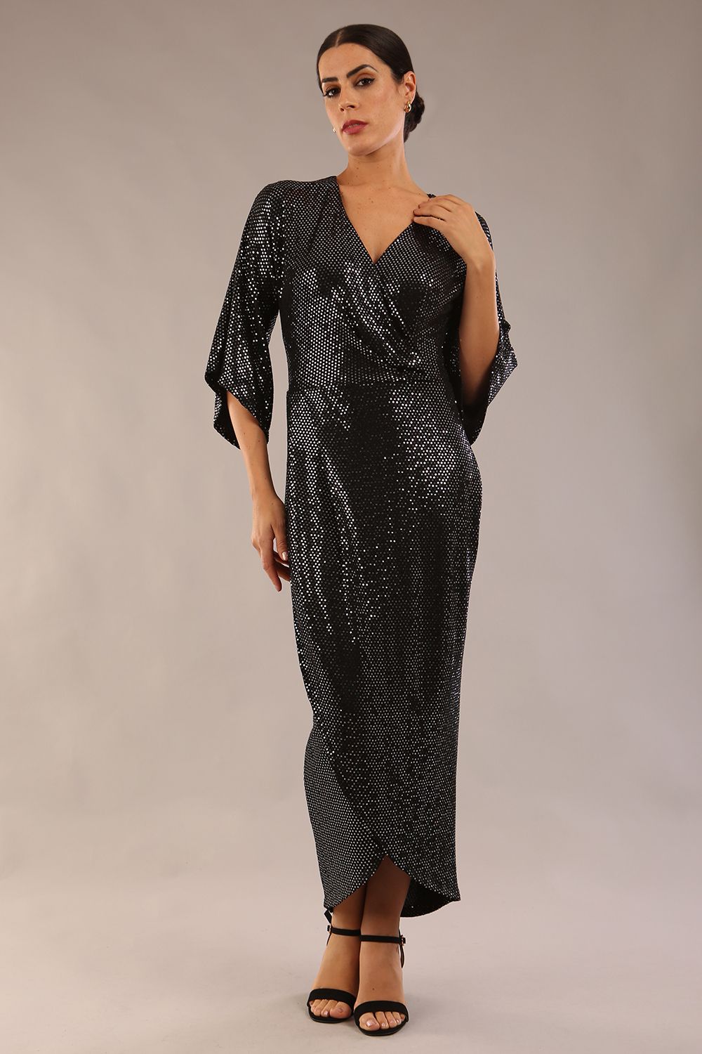 Brunette model wearing diva catwalk Glitterati Midaxi Sparkle Dress in Black in Jersey sparkle and ITY lining with wrap dress style and 3/4 length bell sleeves front