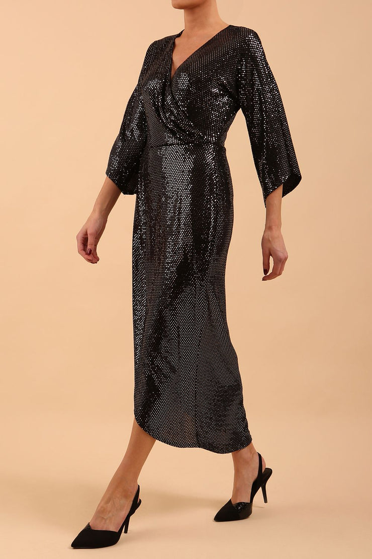Brunette model wearing diva catwalk Glitterati Midaxi Sparkle Dress in Black in Jersey sparkle and ITY lining with wrap dress style and 3/4 length bell sleeves front side