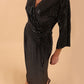 Brunette model wearing diva catwalk Glitterati Midaxi Sparkle Dress in Black in Jersey sparkle and ITY lining with wrap dress style and 3/4 length bell sleeves front  high image