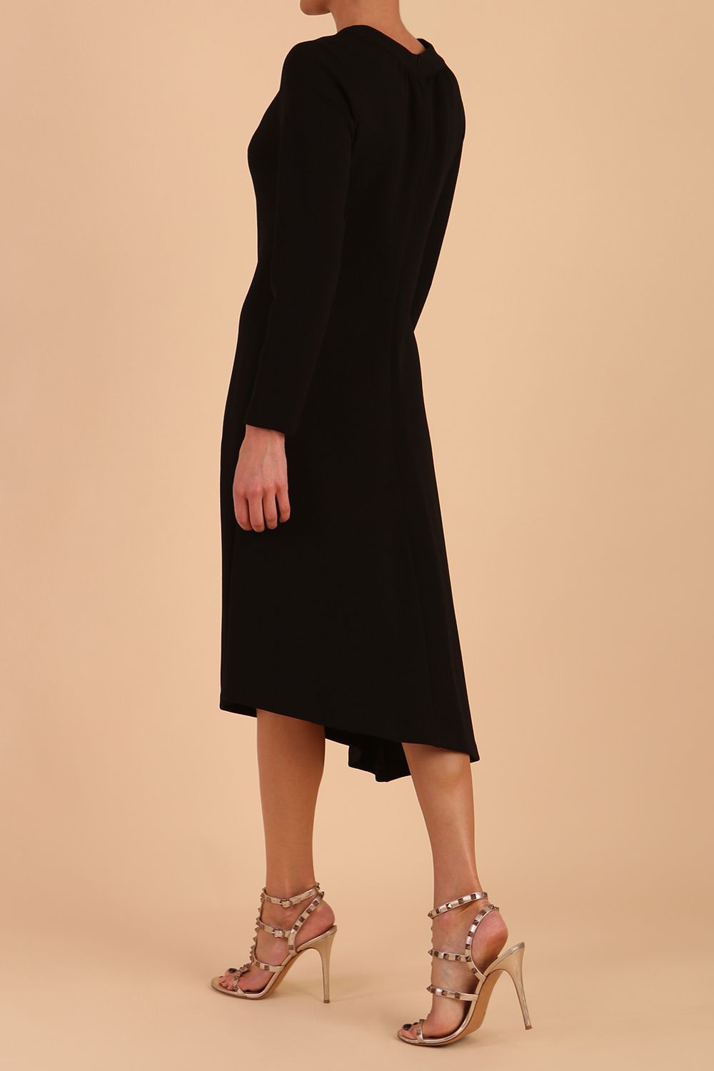 model is wearing diva catwalk dartington asymmetric skirt midaxi long sleeve dress with rounded pleated neckline a-line style in black side back
