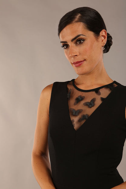 model wearing a Diva Catwalk Patina A-line Swing Sleeveless dress with v-neckline with butterfly detail in Black close up