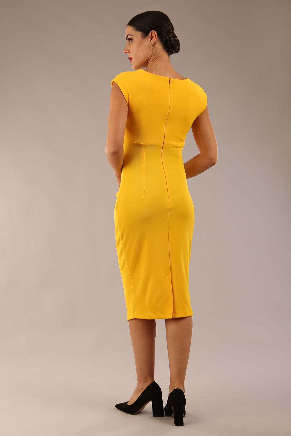 brunette model wearing diva catwalk lydia sleeveless pencil flattering fitted plain dress with split neckline and pleating across the body in spectra yellow back