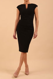 brunette model wearing diva catwalk lydia sleeveless pencil flattering fitted plain dress with split neckline and pleating across the body black front