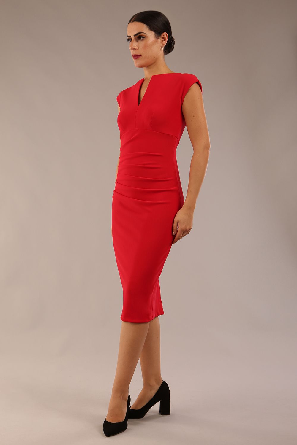 brunette model wearing diva catwalk lydia sleeveless pencil flattering fitted plain dress with split neckline and pleating across the body true red front