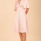 brunette model wearing diva catwalk cambrian satin swing dress with bell short sleeve wide asymmetric waistband and pleating under bust and low v-neckline in pink front