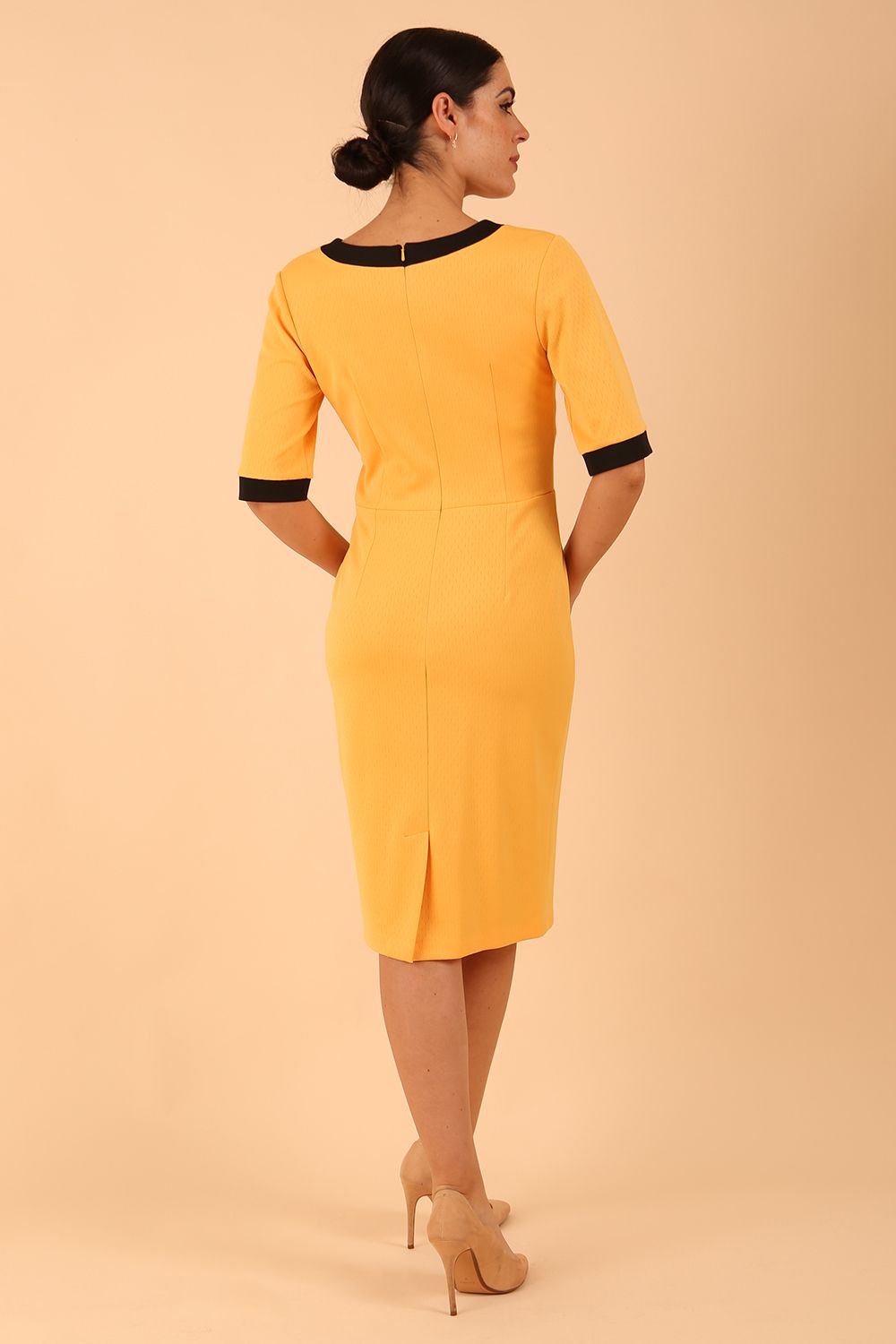 brunette model wearing Diva catwalk goggle pencil dress with short sleeve and v-neckline with contrasted design across body in radiant yellow back