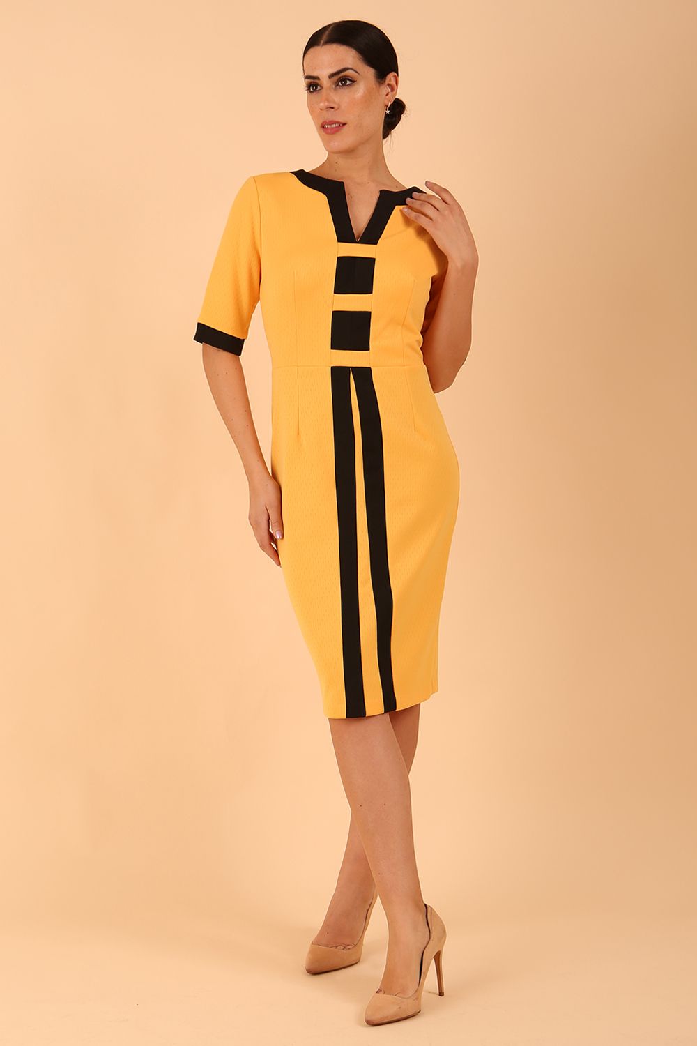 brunette model wearing Diva catwalk goggle pencil dress with short sleeve and v-neckline with contrasted design across body in radiant yellow front