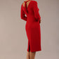 brunette model wearing diva catwalk wimpole a-line flattering dress with lowered v-neck and three quarter sleeve and cinching waistband and widened skirt with pleating in scarlet red back side