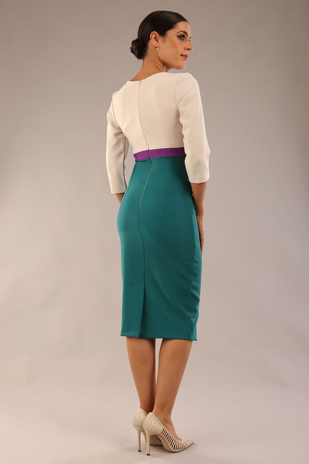 brunette model wearing seed lara pencil colour block dress three quarter sleeve and pleating across the body with split neckline in Pacific green and sandy cream and amethyst purple back