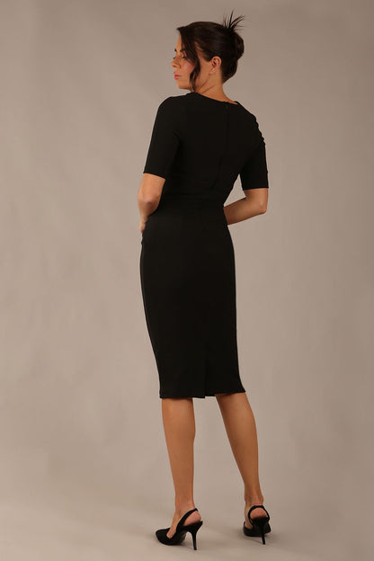 brunette model is wearing a Diva Catwalk Lydia Short Sleeve Pencil Dress with pleating across the tummy and split neckline in Black colour back