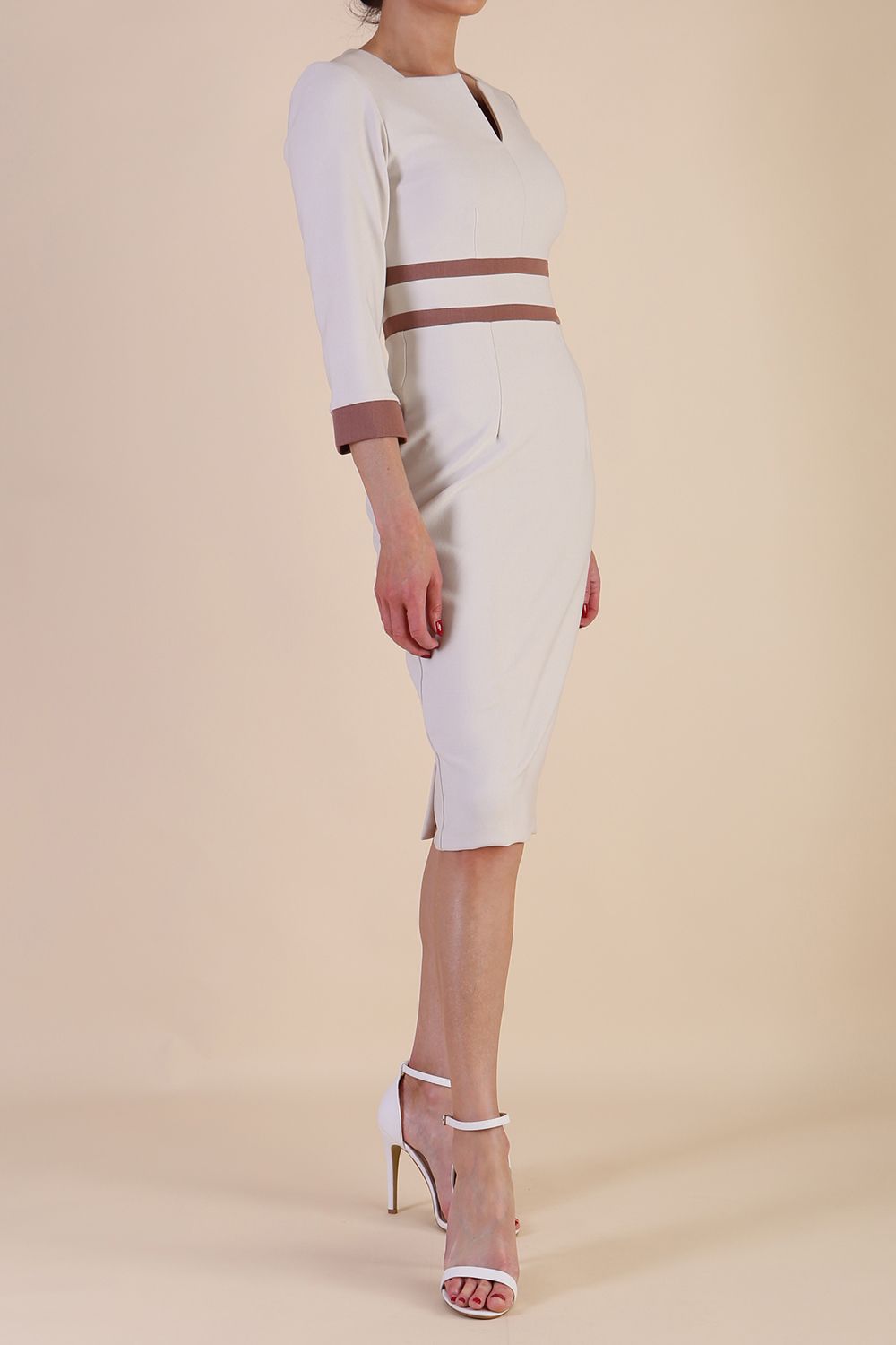 brunette model wearing Diva catwalk Paeonia dress square neckline with a vent in sandshell beige with Acorn Brown and sandshell beige stripes around the waist and three quarter sleeve with Acorn Brown contrast finish front side