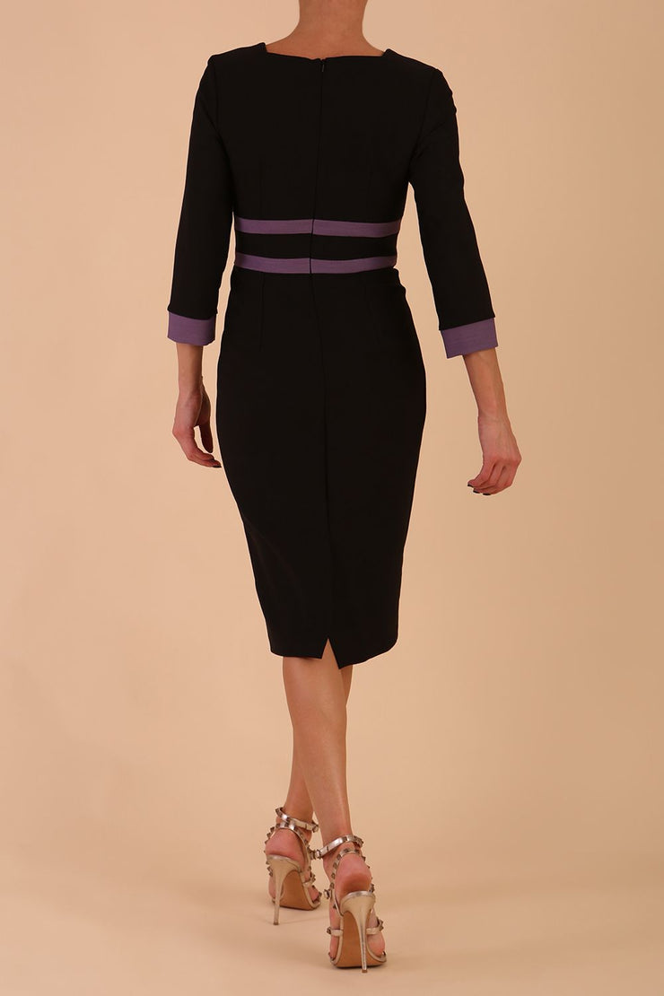 brunette model wearing Diva catwalk Paeonia dress square neckline with a vent in black with Dusky Lilac and black stripes around the waist and three quarter sleeve with Dusky Lilac contrast finish back