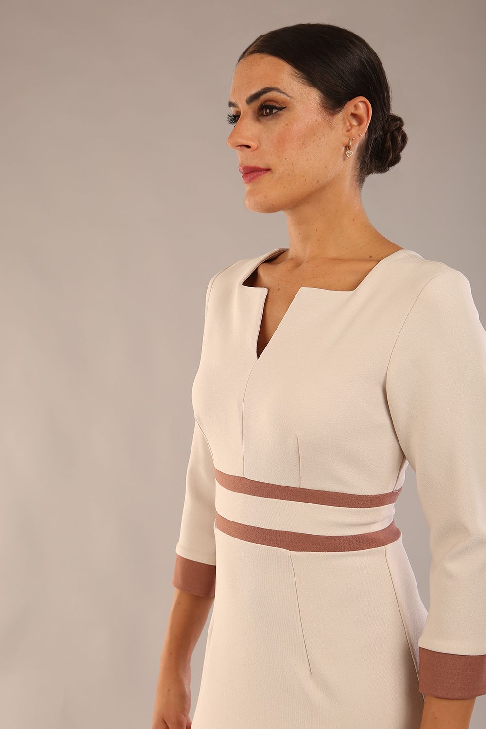 brunette model wearing Diva catwalk Paeonia dress square neckline with a vent in sandshell beige with Acorn Brown and sandshell beige stripes around the waist and three quarter sleeve with Acorn Brown contrast finish front close up