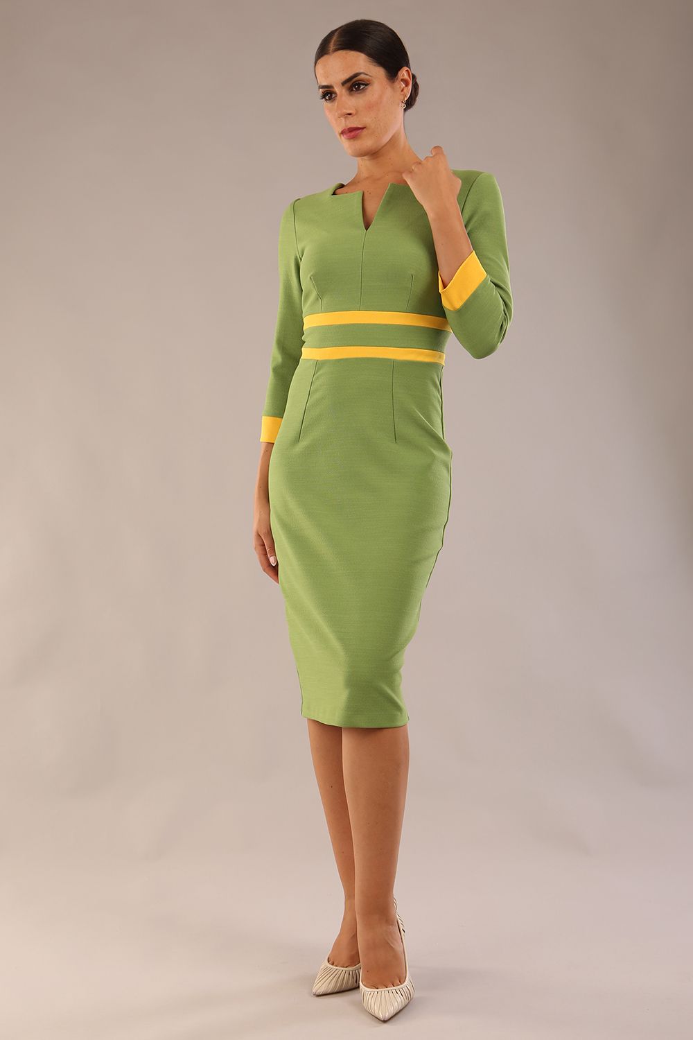 Model wearing Diva catwalk Paeonia dress square neckline with a vent in Citrus Green with Daffodil Yellow and Citrus Green stripes around the waist and three quarter sleeve with Daffodil Yellow contrast finish front