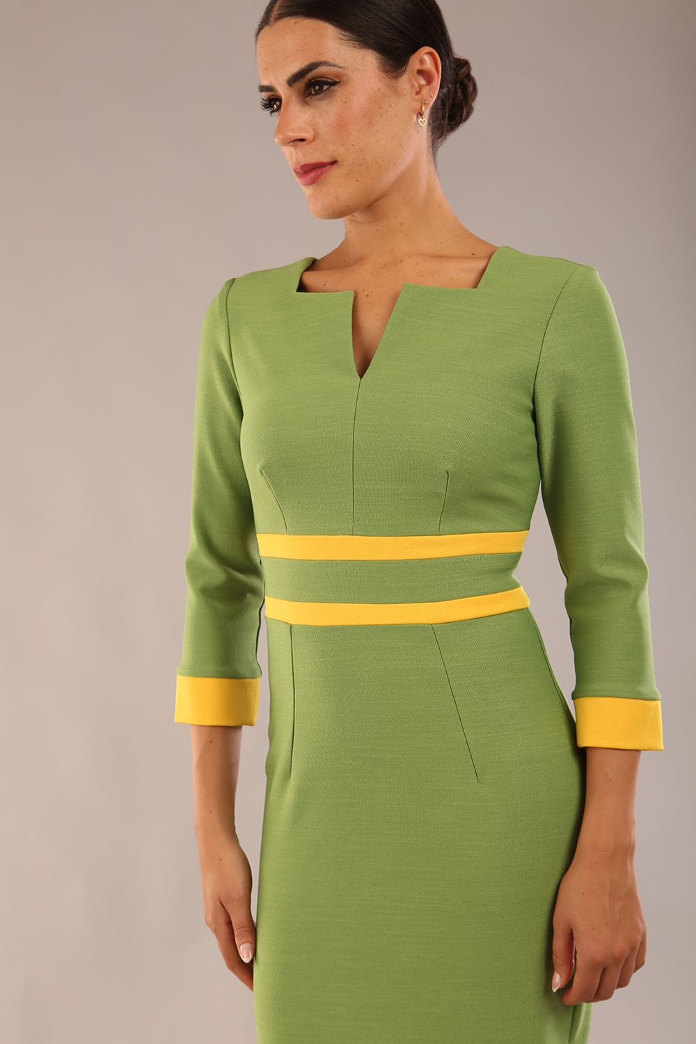 Model wearing Diva catwalk Paeonia dress square neckline with a vent in Citrus Green with Daffodil Yellow and Citrus Green stripes around the waist and three quarter sleeve with Daffodil Yellow contrast finish front close up