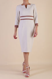brunette model wearing Diva catwalk Paeonia dress square neckline with a vent in sandshell beige with Acorn Brown and sandshell beige stripes around the waist and three quarter sleeve with Acorn Brown contrast finish front