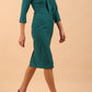 brunette model wearing diva catwalk cranston pencil-skirt dress with low v-neck and tie detail wide band with sleeves in pacific green colour front side