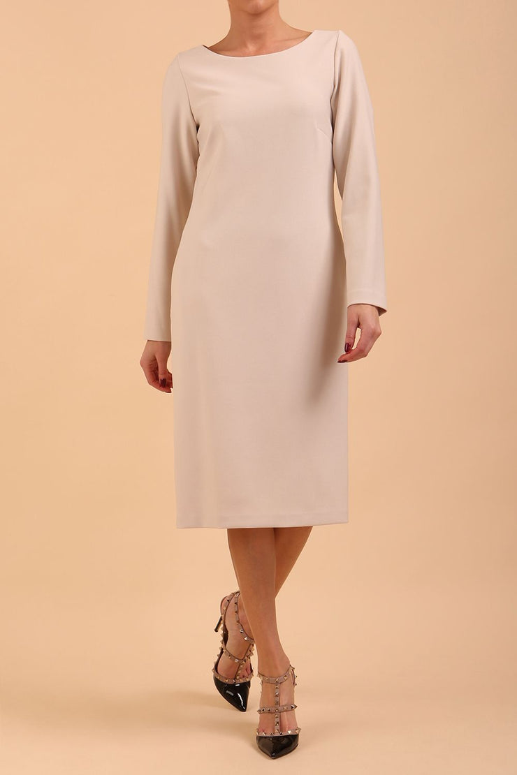 brunette model wearing diva catwalk cora white pencil dress with long sleeves and rounded neckline with pockets in colour sandy cream on front