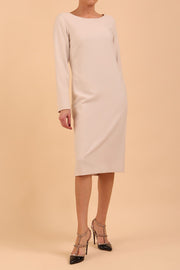 brunette model wearing diva catwalk cora white pencil dress with long sleeves and rounded neckline with pockets in colour sandy cream on front