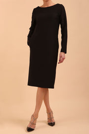 brunette model wearing diva catwalk cora white pencil dress with long sleeves and rounded neckline with pockets in colour black on front