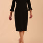 brunette model wearing diva catwalk adriana pencil dress with low v-neck and pleating around shoulders with three quarter sleeve detailed on end and wide waistband in black front