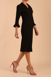 brunette model wearing diva catwalk adriana pencil dress with low v-neck and pleating around shoulders with three quarter sleeve detailed on end and wide waistband in black side