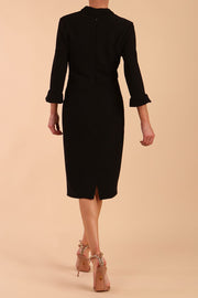 brunette model wearing diva catwalk adriana pencil dress with low v-neck and pleating around shoulders with three quarter sleeve detailed on end and wide waistband in black back