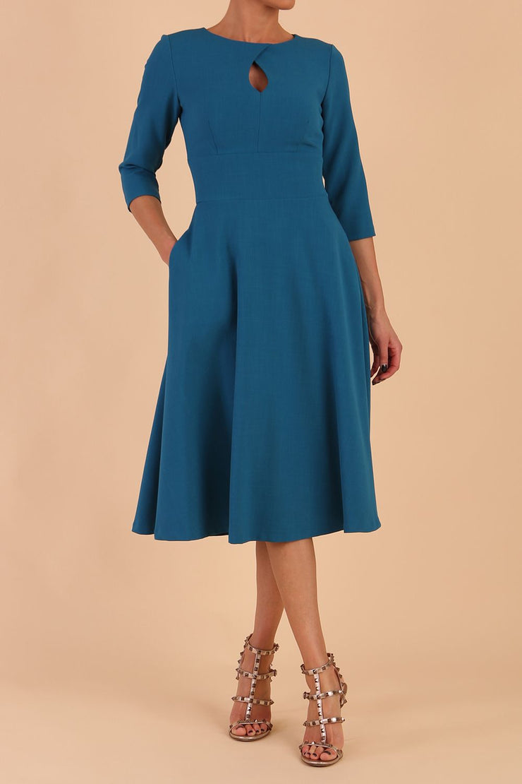 Brunette model is wearing diva catwalk casares swing dress with a keyhole neckline three quarter sleeve dress with pocket detail in Teal front