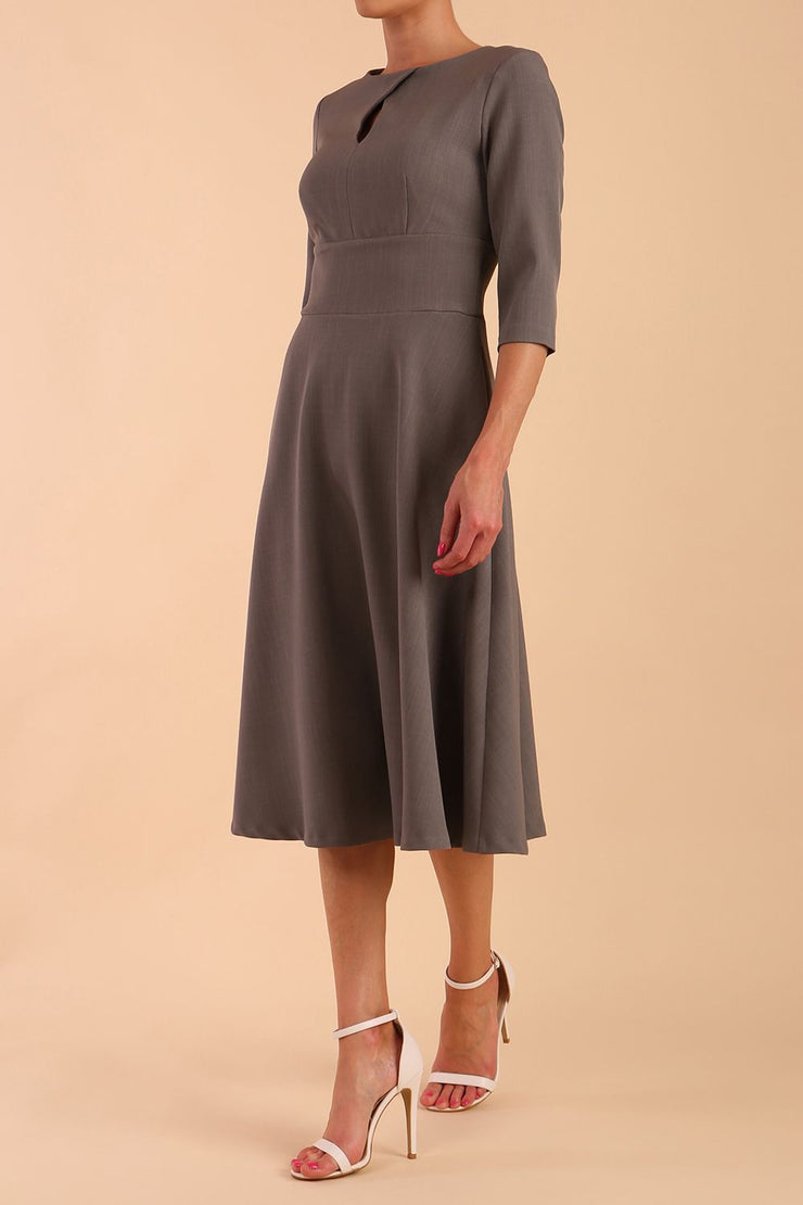 Brunette model is wearing diva catwalk casares swing dress with a keyhole neckline three quarter sleeve dress with pocket detail in Castlerock Grey side front