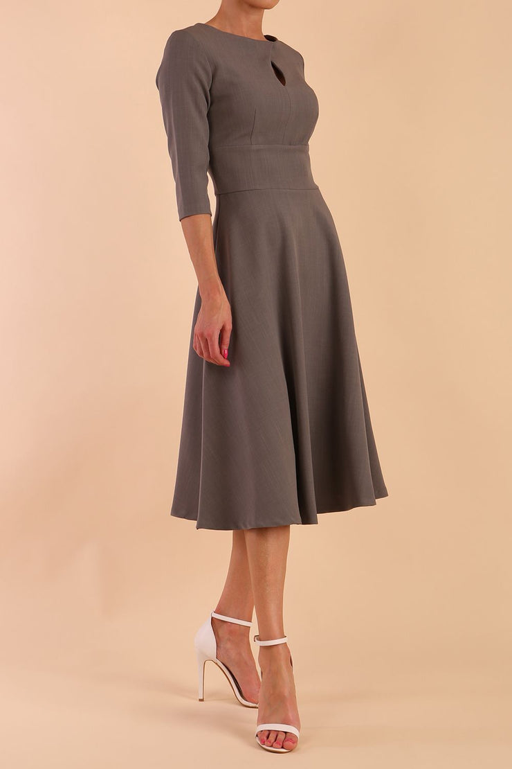 Brunette model is wearing diva catwalk casares swing dress with a keyhole neckline three quarter sleeve dress with pocket detail in Castlerock Grey side front