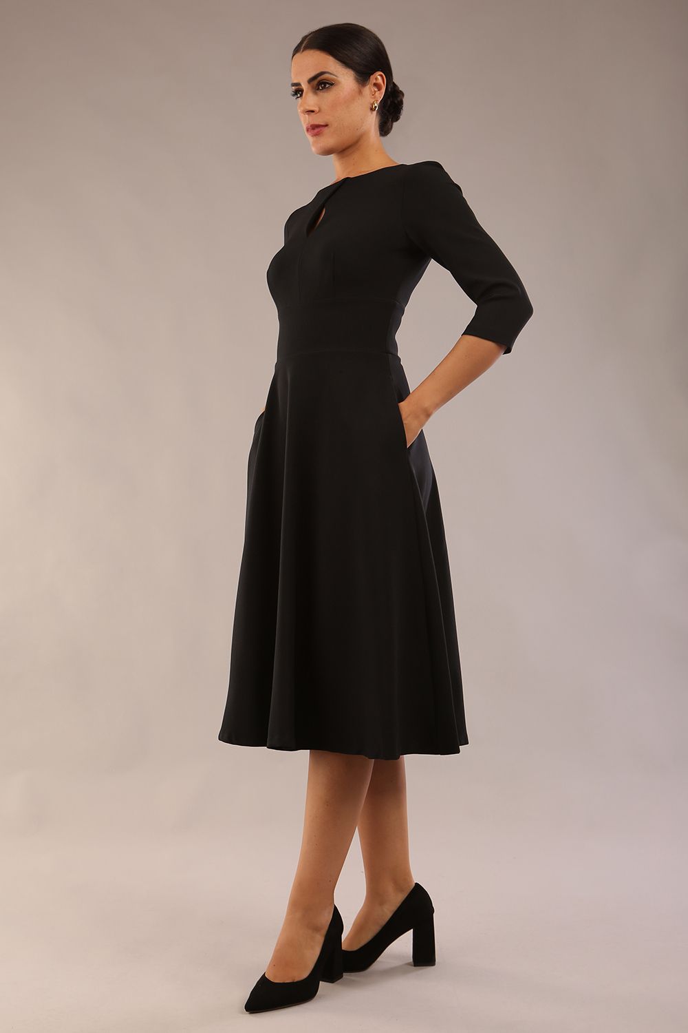 Brunette model is wearing diva catwalk casares swing dress with a keyhole neckline three quarter sleeve dress with pocket detail in black front