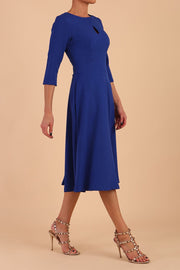 Brunette model is wearing diva catwalk casares swing dress with a keyhole neckline three quarter sleeve dress with pocket detail in Cobalt Blue side front