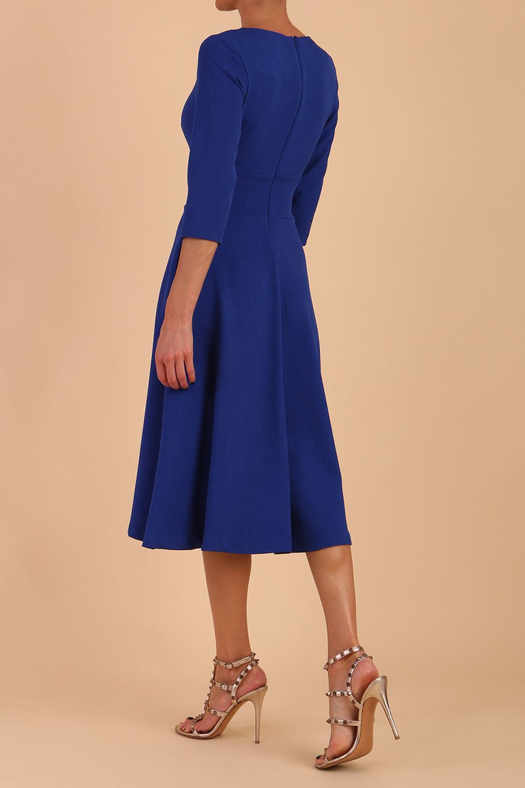 Brunette model is wearing diva catwalk casares swing dress with a keyhole neckline three quarter sleeve dress with pocket detail in Cobalt Blue back