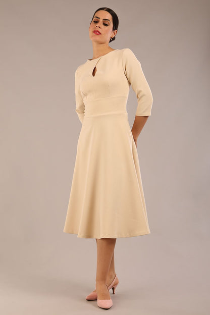 Brunette model is wearing diva catwalk casares swing dress with a keyhole neckline three quarter sleeve dress with pocket detail in Sandshell Beige front