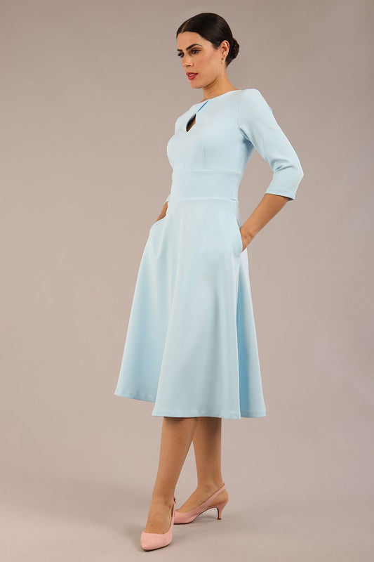Brunette model is wearing diva catwalk casares swing dress with a keyhole neckline three quarter sleeve dress with pocket detail in Sky Blue front side