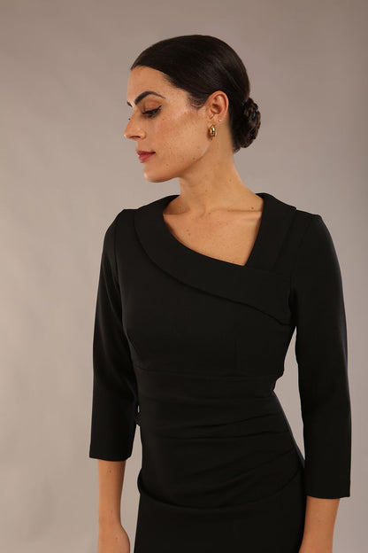 model is wearing a diva catwalk ed pencil three quarter sleeve dress with asymmetric neckline and pleating around tummy area front image black colour close up