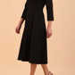 A model is wearing a swing black three quarter sleeve dress with oversized collar and pockets in the skirt