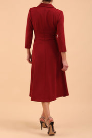 A model is wearing a swing wine three quarter sleeve dress with oversized collar and pockets in the skirt