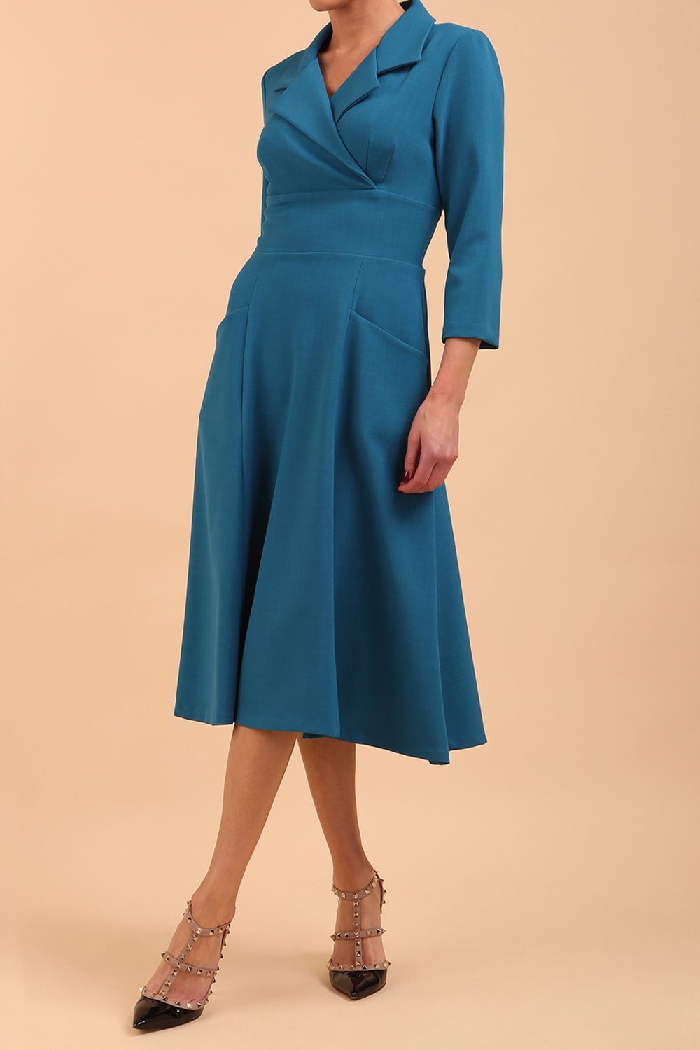 A model is wearing a swing wine three quarter sleeve dress with oversized collar and pockets in the skirt