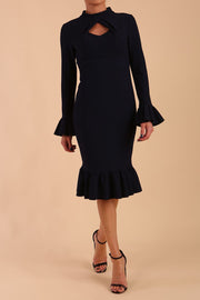 Model wearing Macarena Peplum Hem Bodycon Pencil Dress with Long sleeves with peplum details at the ends and High neckline with overlapping keyhole detail in Dark Navy colour front 
