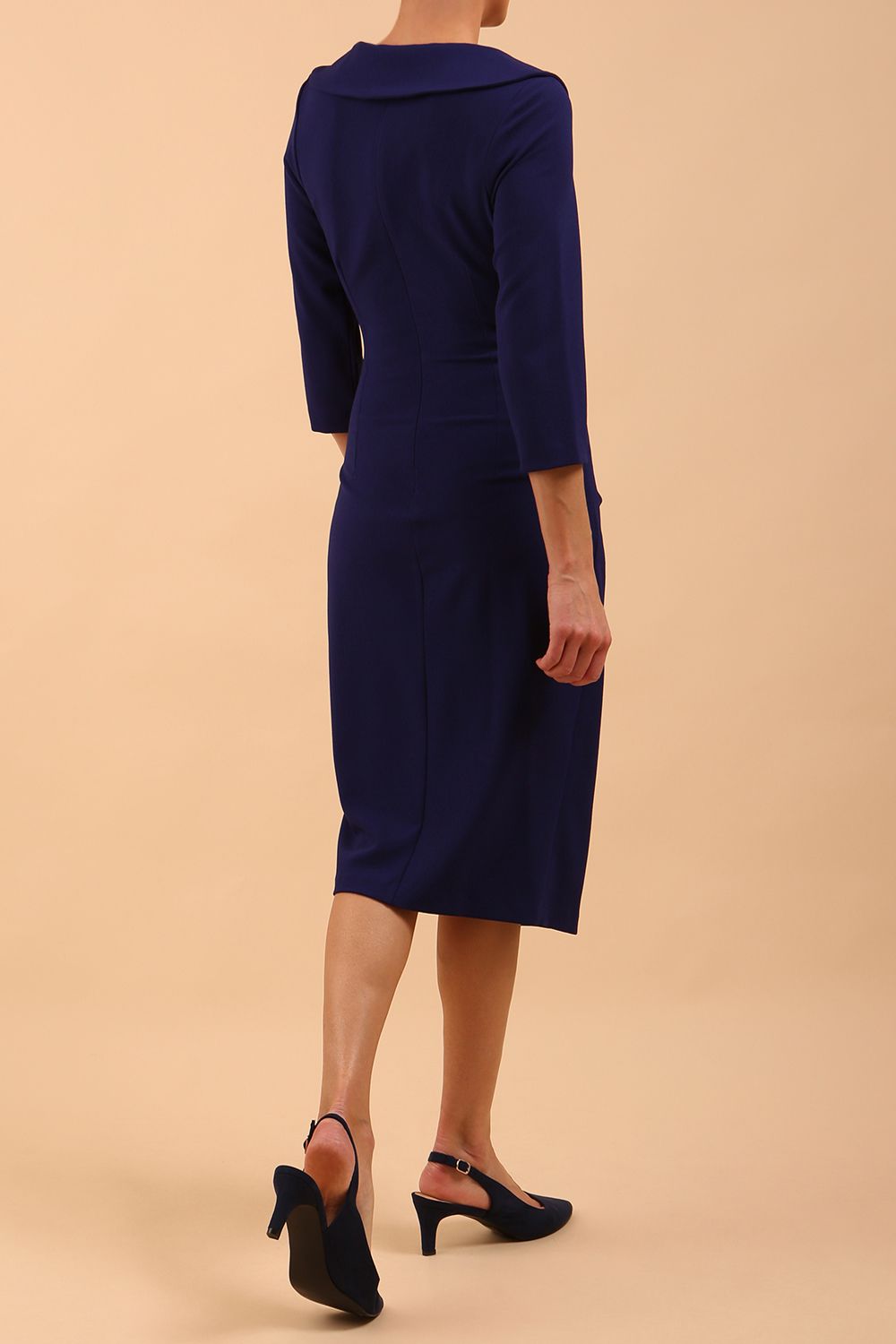  model is wearing diva catwalk liesel wrap pencil sleeved dress with collar half way around low v-neck in oxford blue back