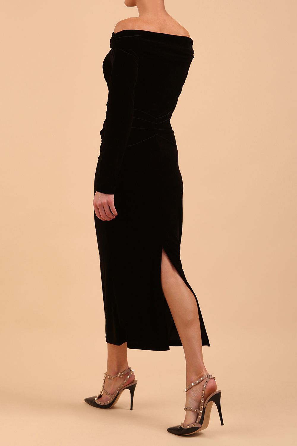 A Model is wearing an off shoulder bardot neckline velvet stretch midi dress in black by diva catwalk back