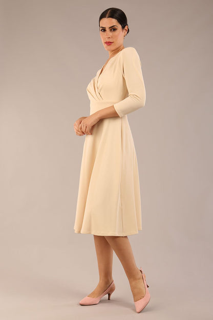 brunette model is wearing a diva catwalk january sleeved a-line swing v-neck dress in marvel fabric in beige colour front 