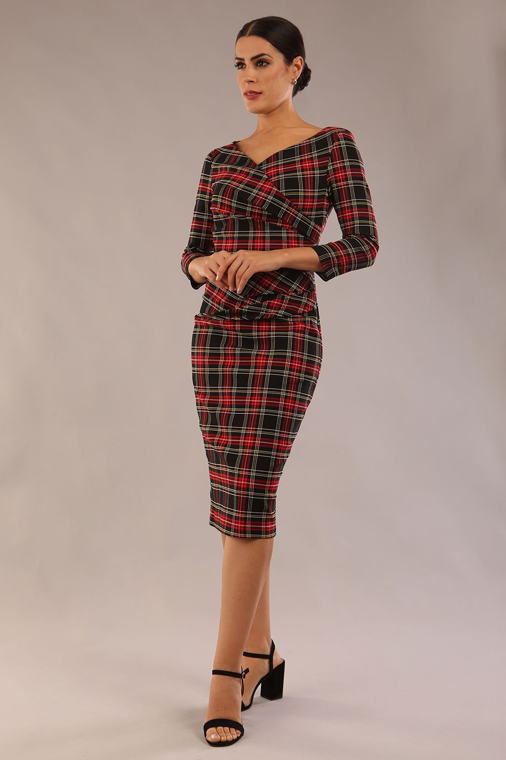 model is wearing a diva catwalk Horizon Tartan Stretch Pencil Dress with crossover v neckline and 3/4 sleeves and pleating details and knee length in luxury tartan stretch fabric in Royal Red Tartan